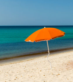 Parasol at beach against clear sky