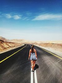 Rear view of woman standing on road against sky