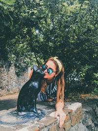 Young woman with dog against trees and plants