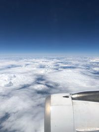 Airplane flying over clouds against blue sky