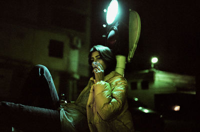 Portrait of young man holding camera at night