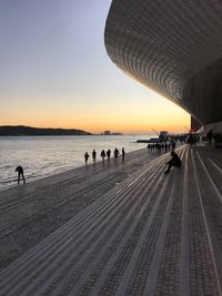 People on beach in city against clear sky