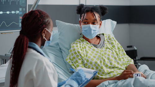 Doctor wearing mask consulting patient at hospital