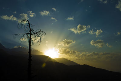 Silhouette landscape against mountains at sunset