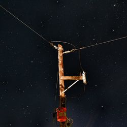 Low angle view of illuminated electricity pylon against star field in sky at night