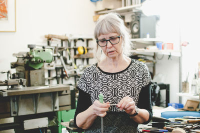 Senior woman holding work tool in jewelry workshop