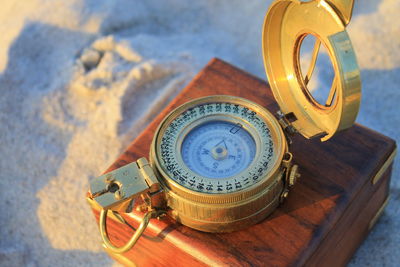 High angle view of compass with box on sand
