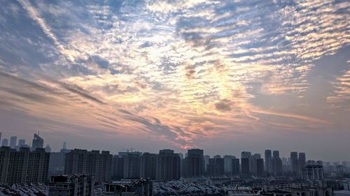 Modern buildings in city against sky during sunset