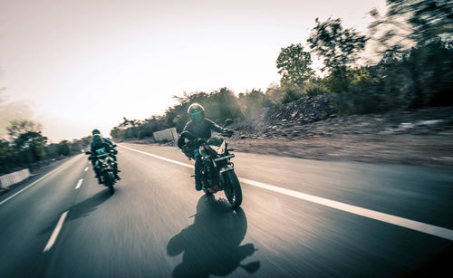 Man riding motorcycle on road against sky