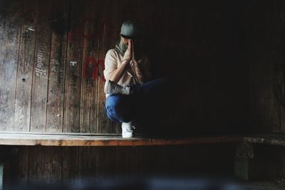 Side view of man sitting on wooden floor