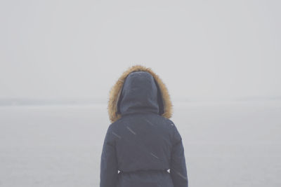 Woman in warm clothing at beach during winter