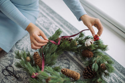 Midsection of woman decorating wreath on floor