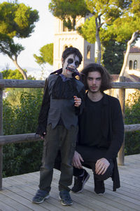 Full length portrait of happy young friends sitting on tree