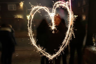 Low angle view of woman with firework display at night