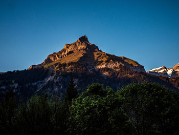 Low angle view of rock formation against clear blue sky