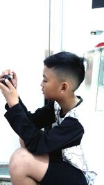 Full length of boy sitting on window at home