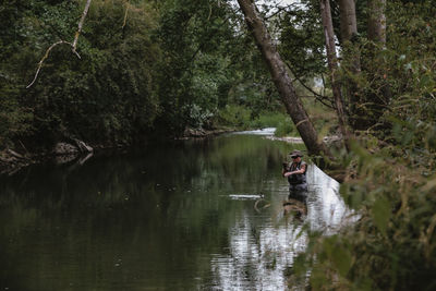 Man in lake amidst trees in forest