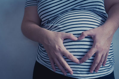 Midsection of pregnant woman touching belly