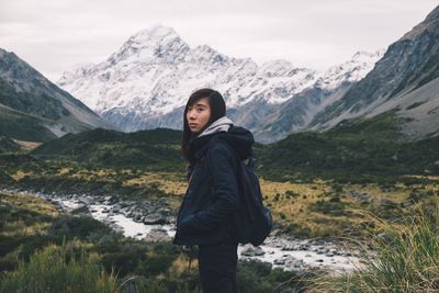 Woman standing on snowcapped mountains against sky