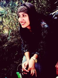 Portrait of smiling young woman against tree