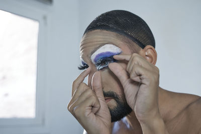 Mid adult man applying eyelash at home