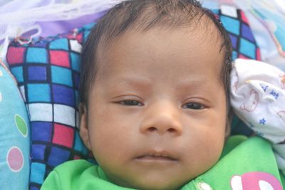 Close-up portrait of cute baby lying on bed