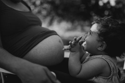 Happy baby girl looking at pregnant mother