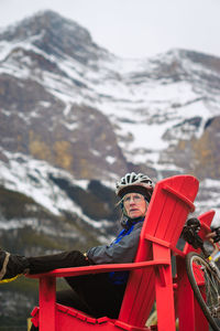 Portrait of mature woman sitting on red deck chair at banff national park