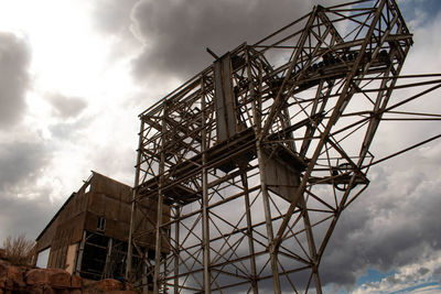 Low angle view of crane at construction site against sky