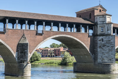 Low angle view of arch bridge over river against buildings