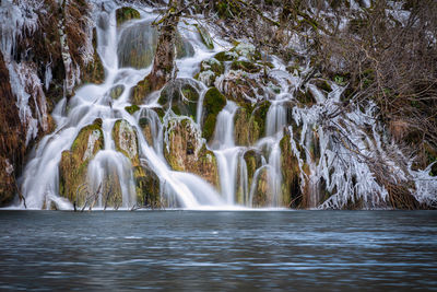 Scenic view of waterfall in forest at winter