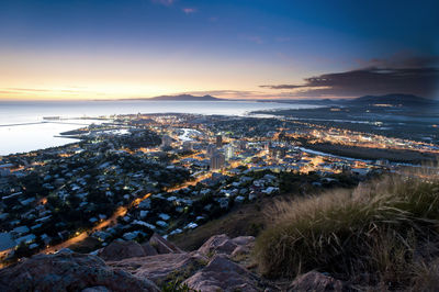 High angle view of townscape by sea against sky at sunset