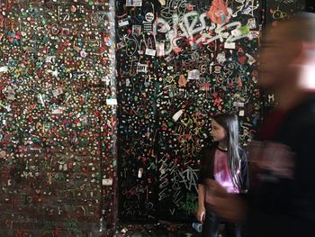 Blurred motion of man by teenage girl standing against gum wall