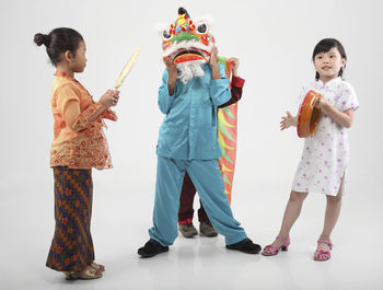Girls by boys wearing costume against white background