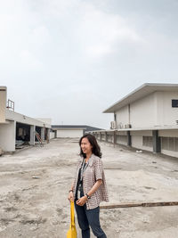 Woman standing by building against sky