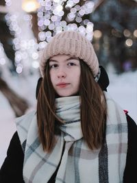 Portrait of young woman standing against christmas tree