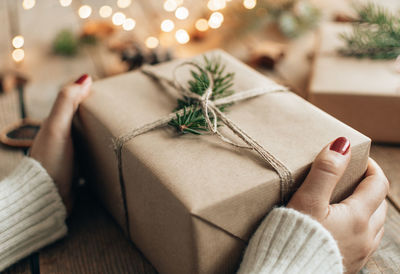 Close-up photo of hands holding christmas present wrapped in brown paper