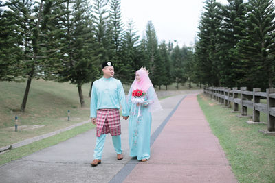 Couple in traditional clothing walking on footpath amidst trees