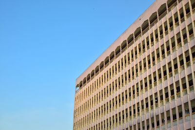 An image of a building with full of windows with blue sky background. 