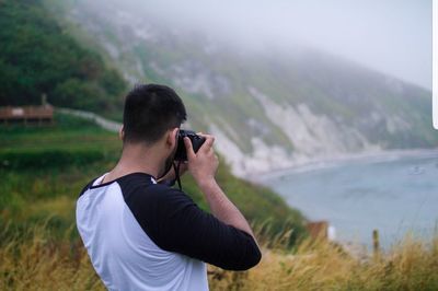 Man photographing lake by mountain