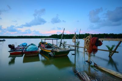 Fishing boats moored in sea against sky