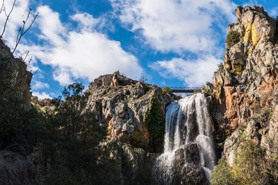 Low angle view of waterfall against sky