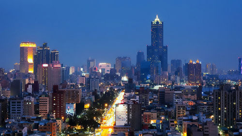 Illuminated cityscape against blue sky