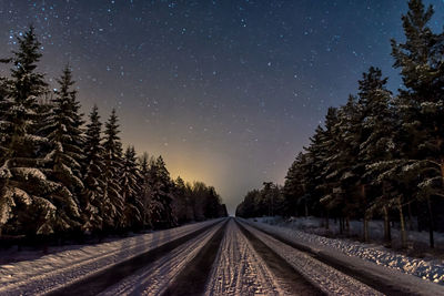 Railroad tracks amidst trees against clear sky during winter