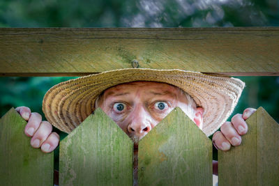 A curious man looks over a garden fence