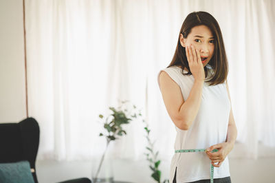 Portrait of woman standing against wall at home