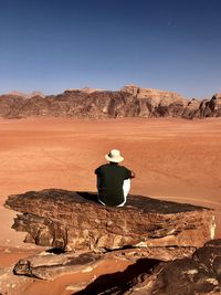 Rear view of man sitting on desert