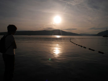 Silhouette man on shore against sky during sunset