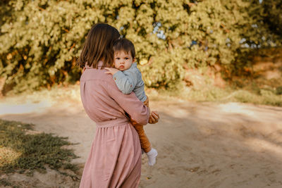 Rear view of mother with daughter standing on land