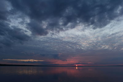 Sunset on the horizon from under glooming looming clouds